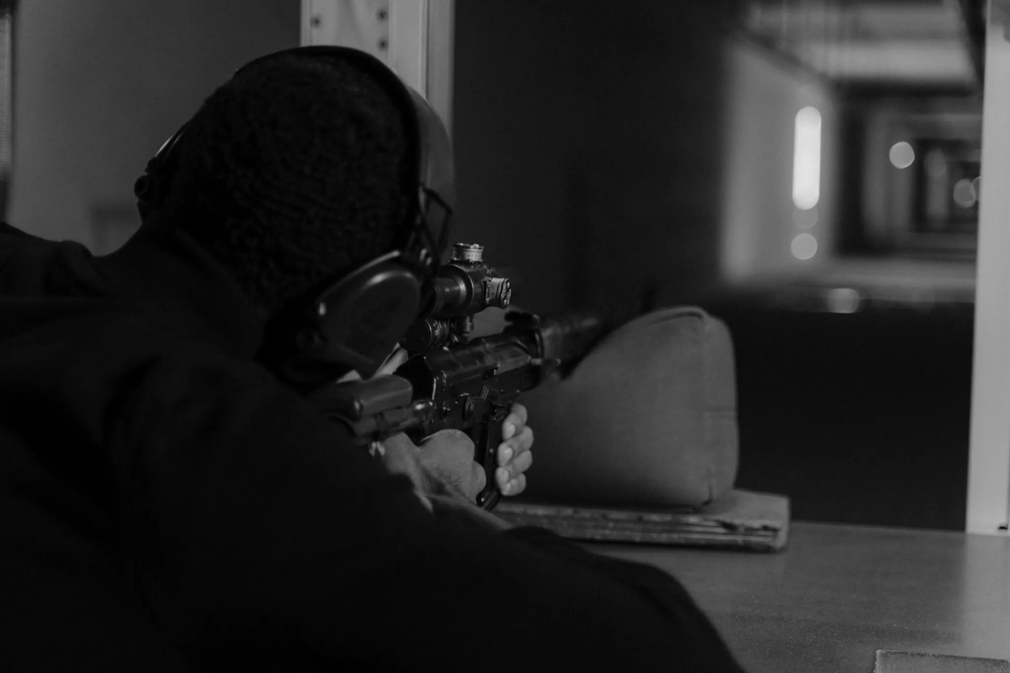Atirador em estande de tiro mirando com rifle